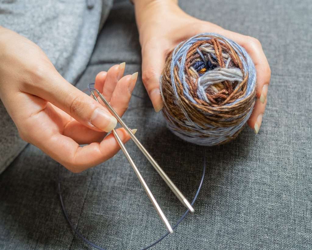 Woman holding circular needles and a ball of yarn